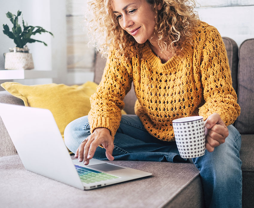Woman holding coffee while on laptop