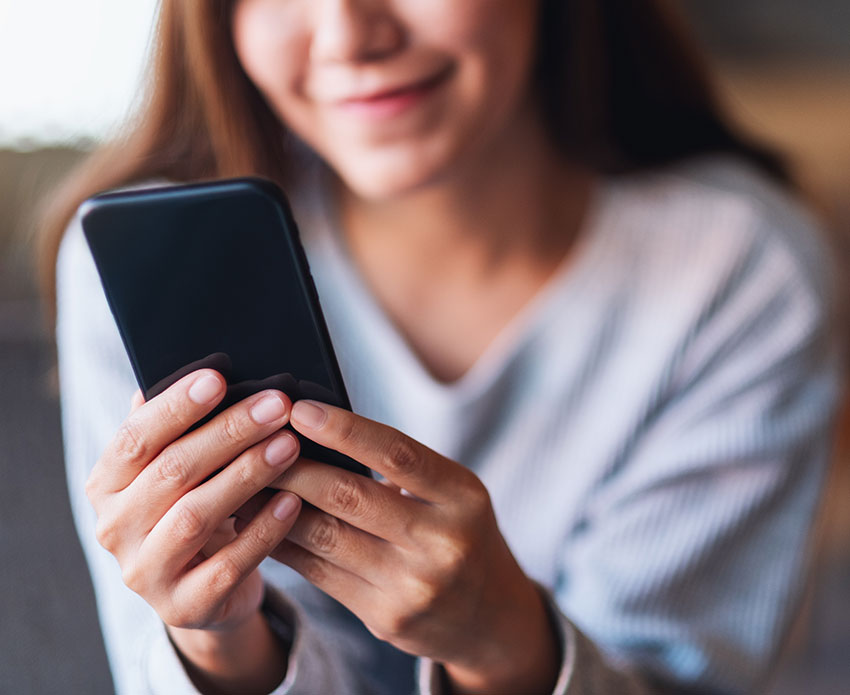Woman holding phone reading and smiling
