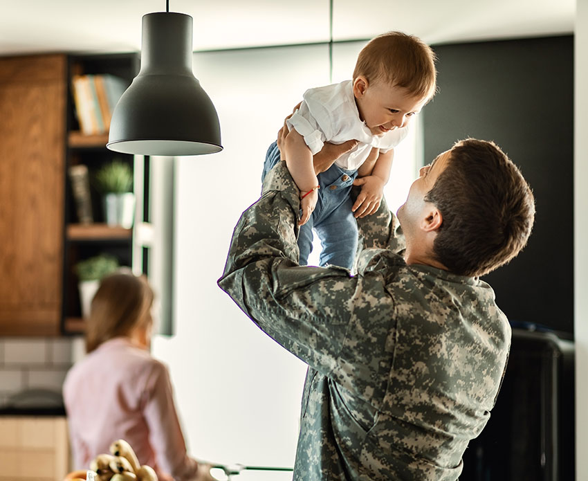 Dad holding son in kitchen wearing service clothing
