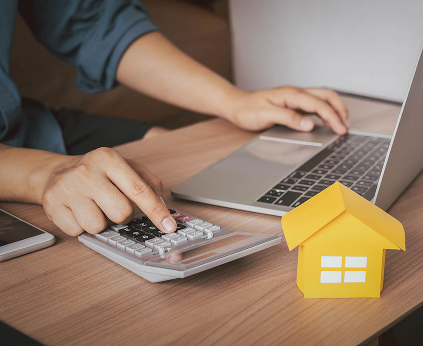 Person using calculator while on laptop with small home display