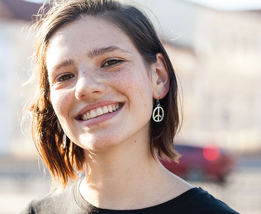 Teen girl smiling with peace sign earring