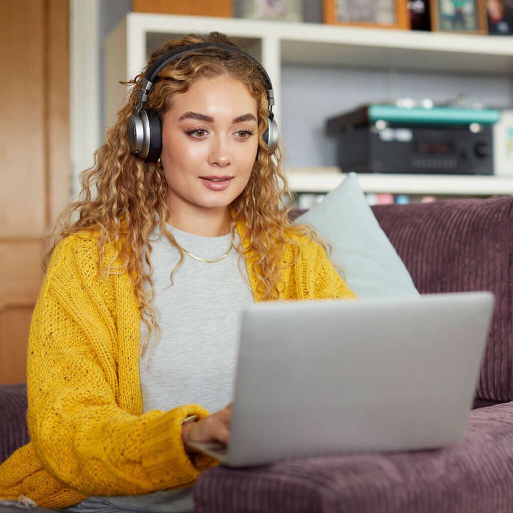 Woman on her laptop with headphones joining mortgage webinars